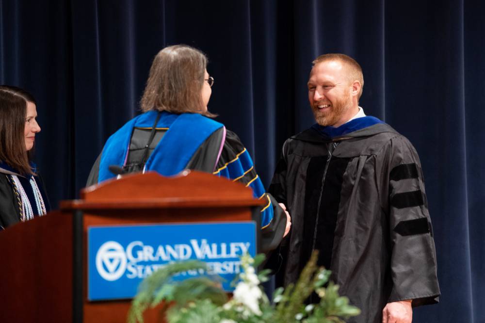 Faculty member smiles while accepting an award as the Provost looks on.